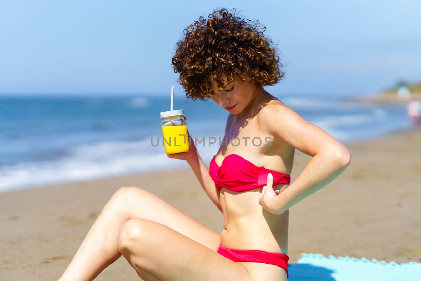 Woman with cool drink chilling on beach by javiindy