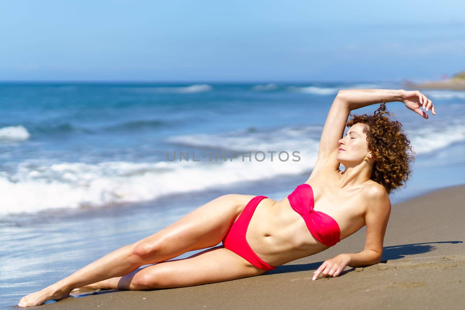 Slim lady in swimsuit suntanning on coast by javiindy