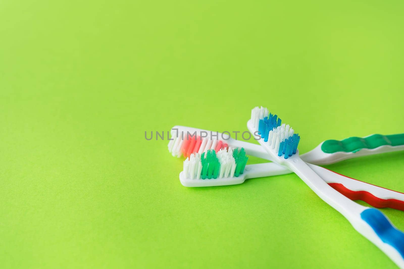 Multicolored toothbrushes on a green background, the concept of dental care and oral hygiene. Place for an inscription