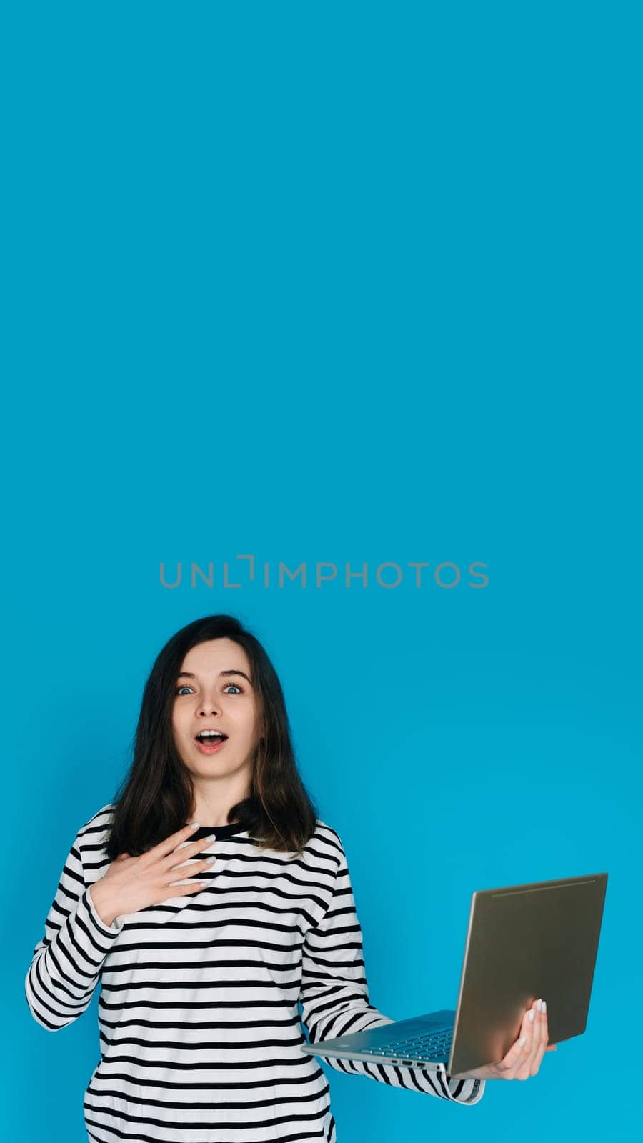 Excited Woman in Striped Sweater Writing Email on Laptop - Modern Technology and Communication Concept. Empty Space for Text - Isolated on Blue Background - Perfect for Business and Technology Themes