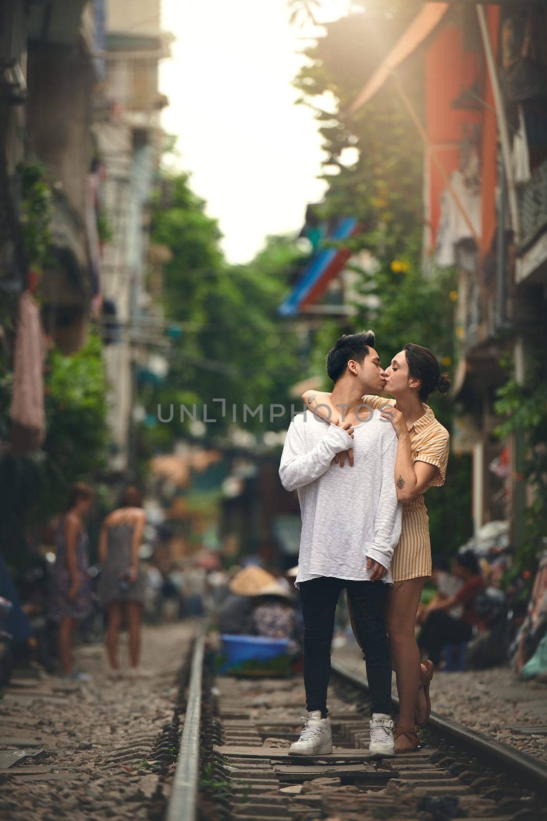 The kind of romance we dream about. a young couple sharing a romantic moment on the train tracks in the streets of Vietnam