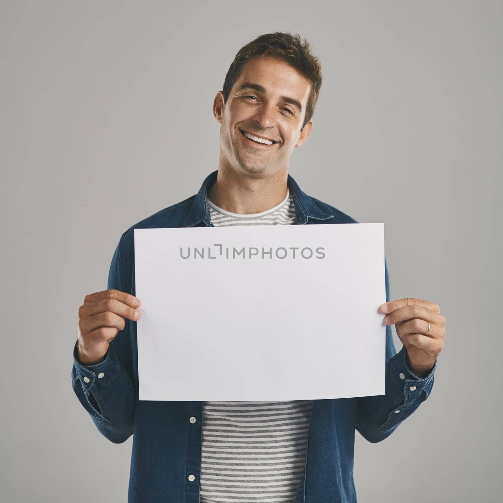 Its time to tell your story. Studio portrait of a young man holding a blank placard against a grey background
