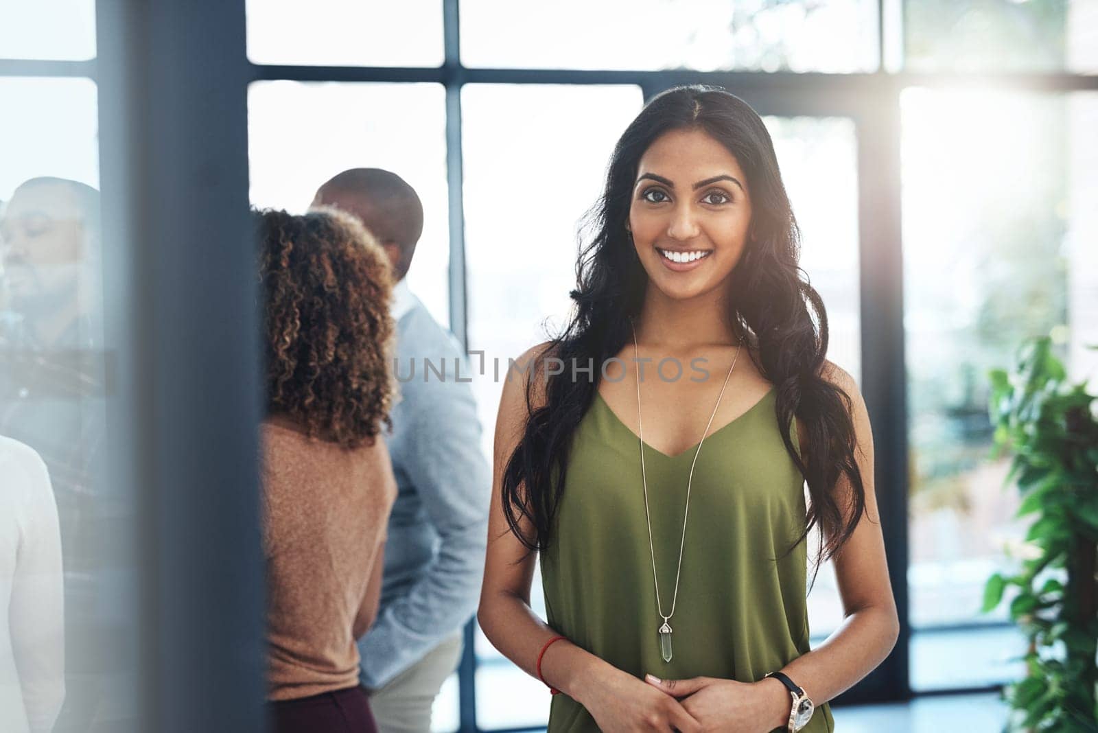 Im part of a great team. Portrait of an attractive young woman standing in the office with her colleagues in the background