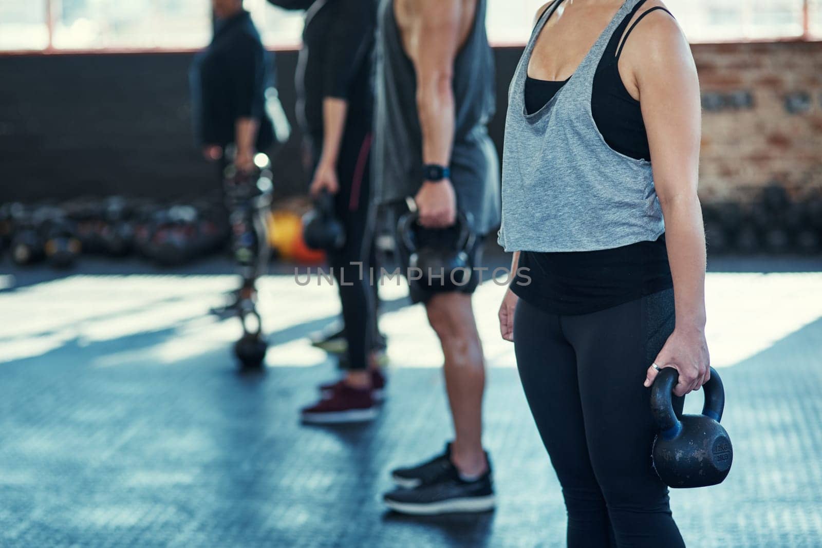 Work those muscles. a group unrecognizable people standing in a row doing training with weights in a gym