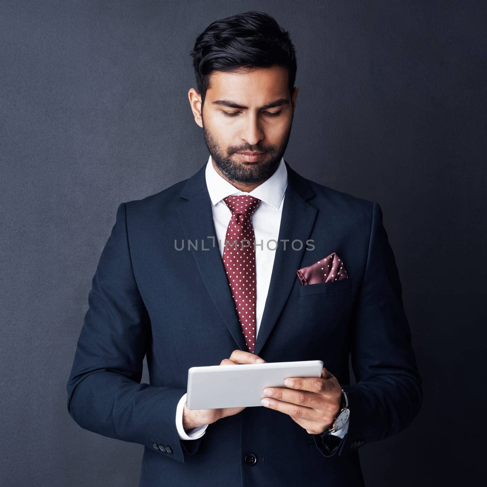 One handy gadget that takes care of the hard work. Studio shot of a businessman using a digital tablet against a gray background. by YuriArcurs