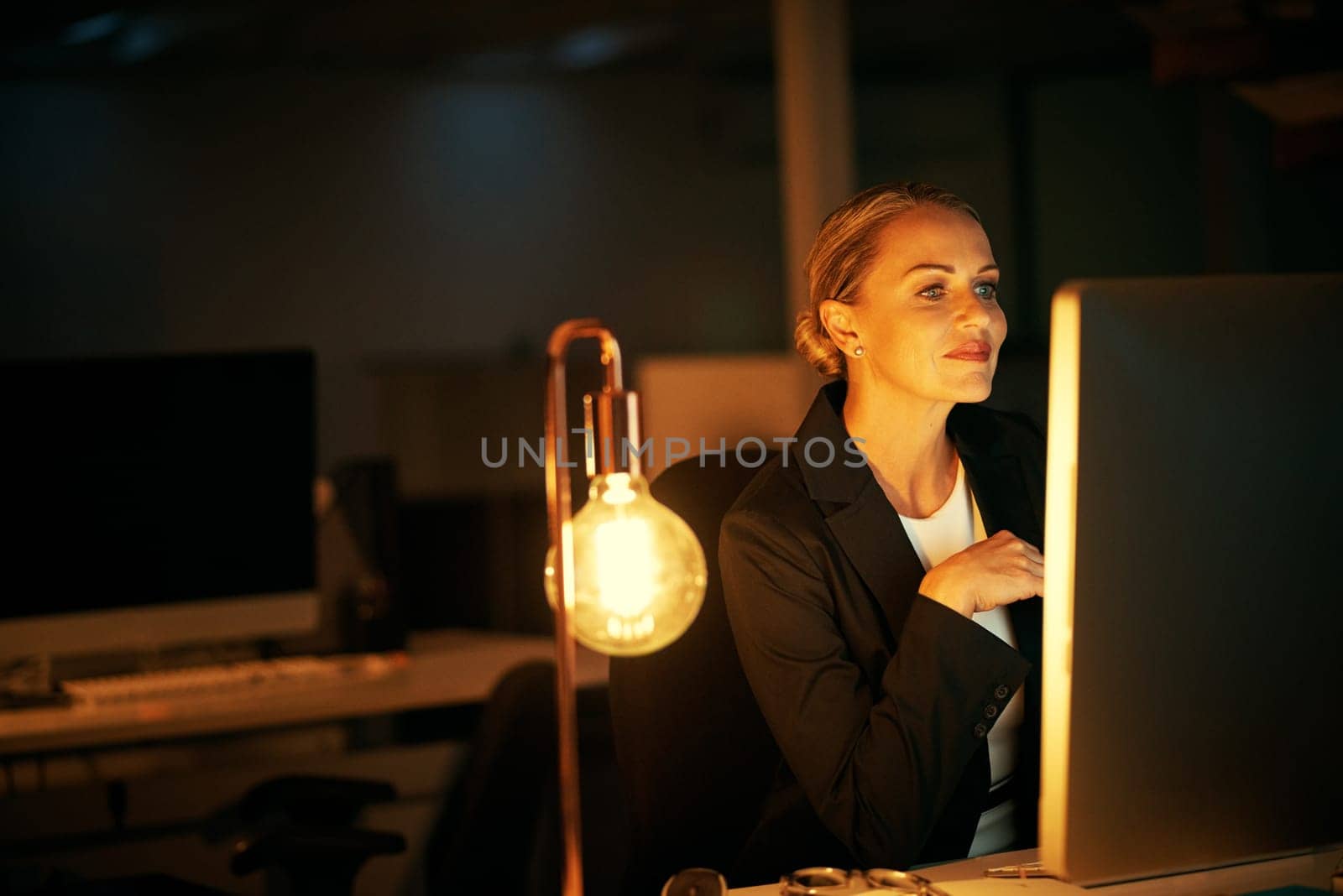 The busy season necessitates more hours. a mature businesswoman working late at the office. by YuriArcurs