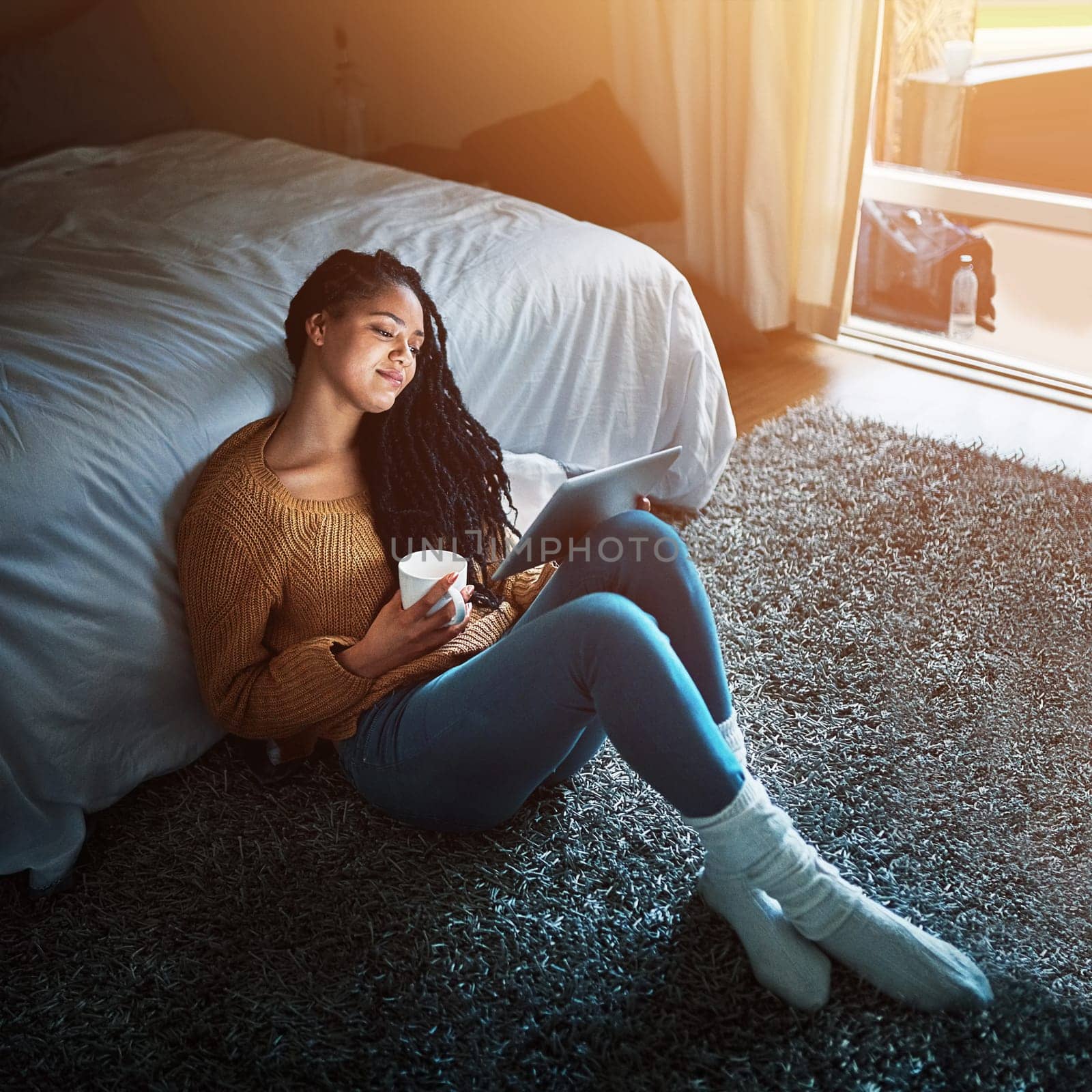 The cure for a long hard day. a relaxed young woman drinking coffee and using a digital tablet at home