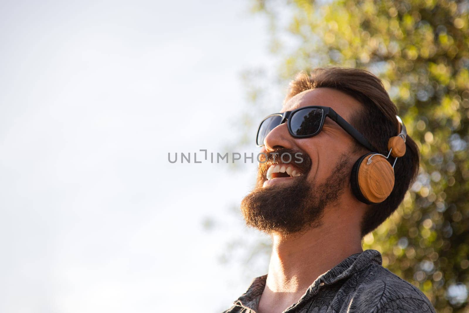 Smiling man relaxing listening to music with headphones surrounded by nature. Copy space. by Hoverstock