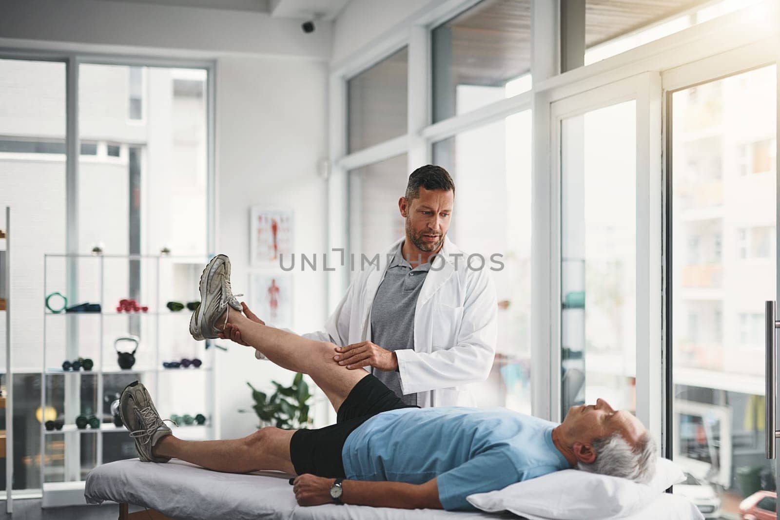 Lets assess where the pain is coming from. a young male physiotherapist assisting a senior patient in recovery. by YuriArcurs