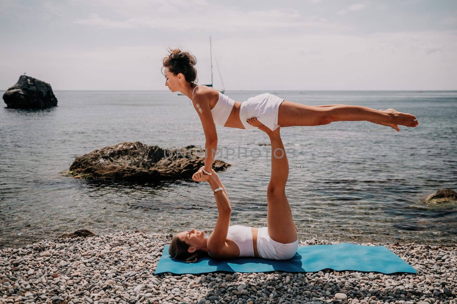 Woman sea yoga. Back view of free calm happy satisfied woman with long hair standing on top rock with yoga position against of sky by the sea. Healthy lifestyle outdoors in nature, fitness concept.