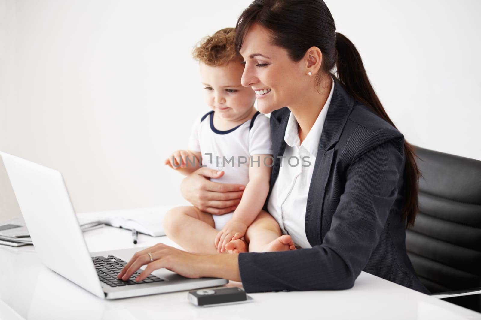 Remote work, laptop and a mother with care of a baby while working, typing email and doing research. Happy, business and a mom with a computer for entrepreneurship while caring for a child in a house by YuriArcurs