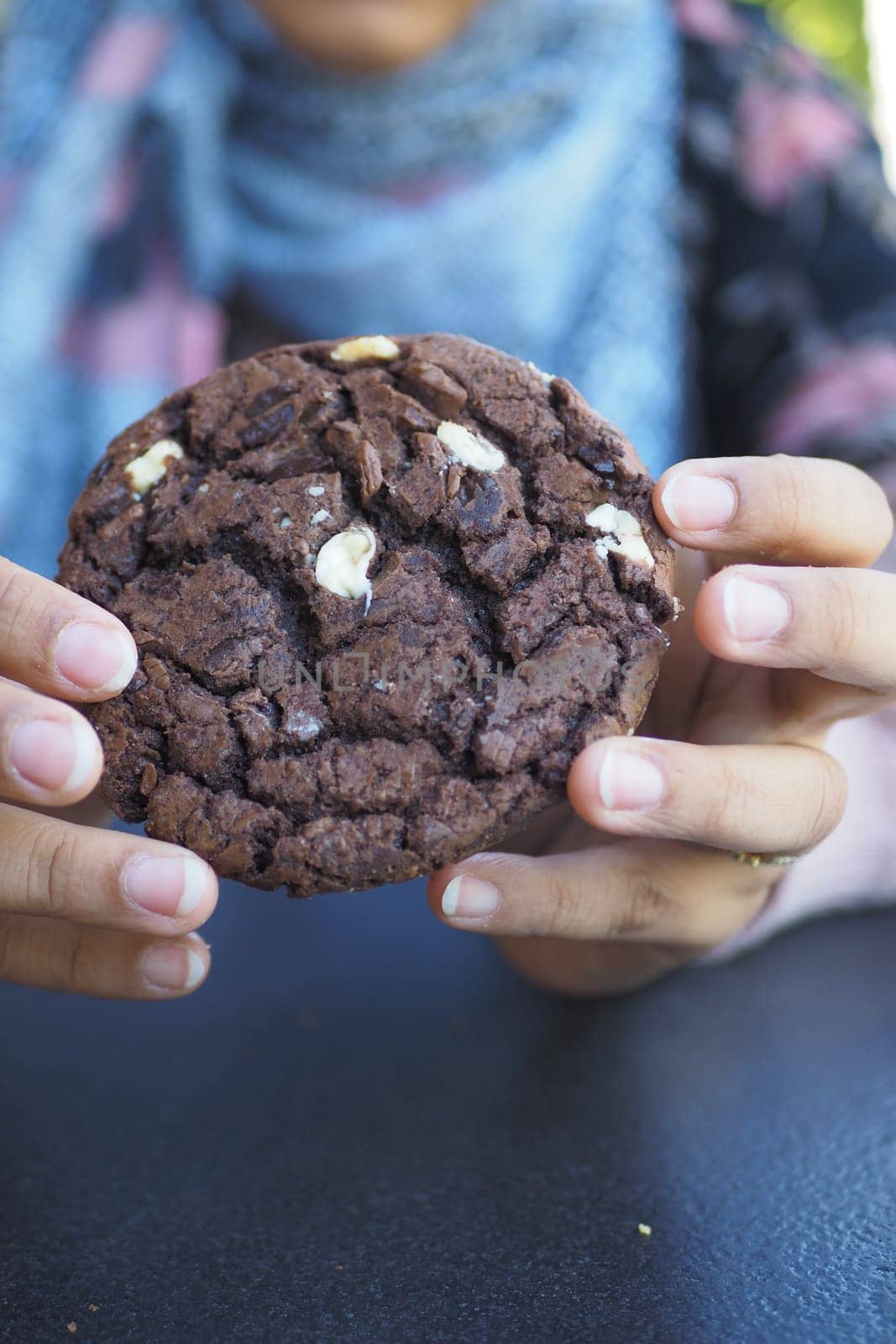 women holding a chocolate cookies .
