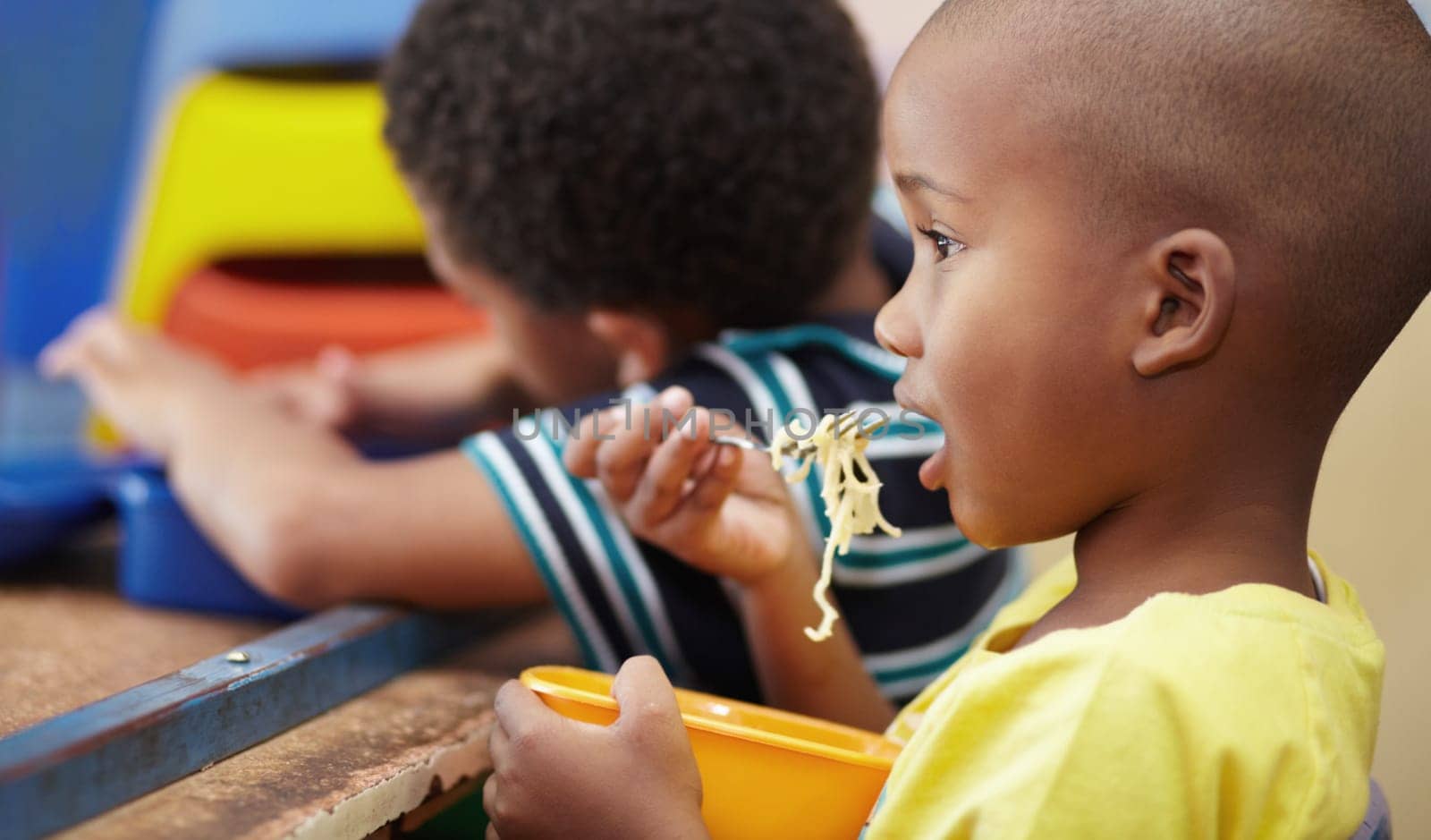 Child, lunch and eating in school, kindergarten or classroom and healthy nutrition, food and noodles. Kids, black boy and hungry kid or eat snack, pasta in lunchbox or breakfast in kindergarden.
