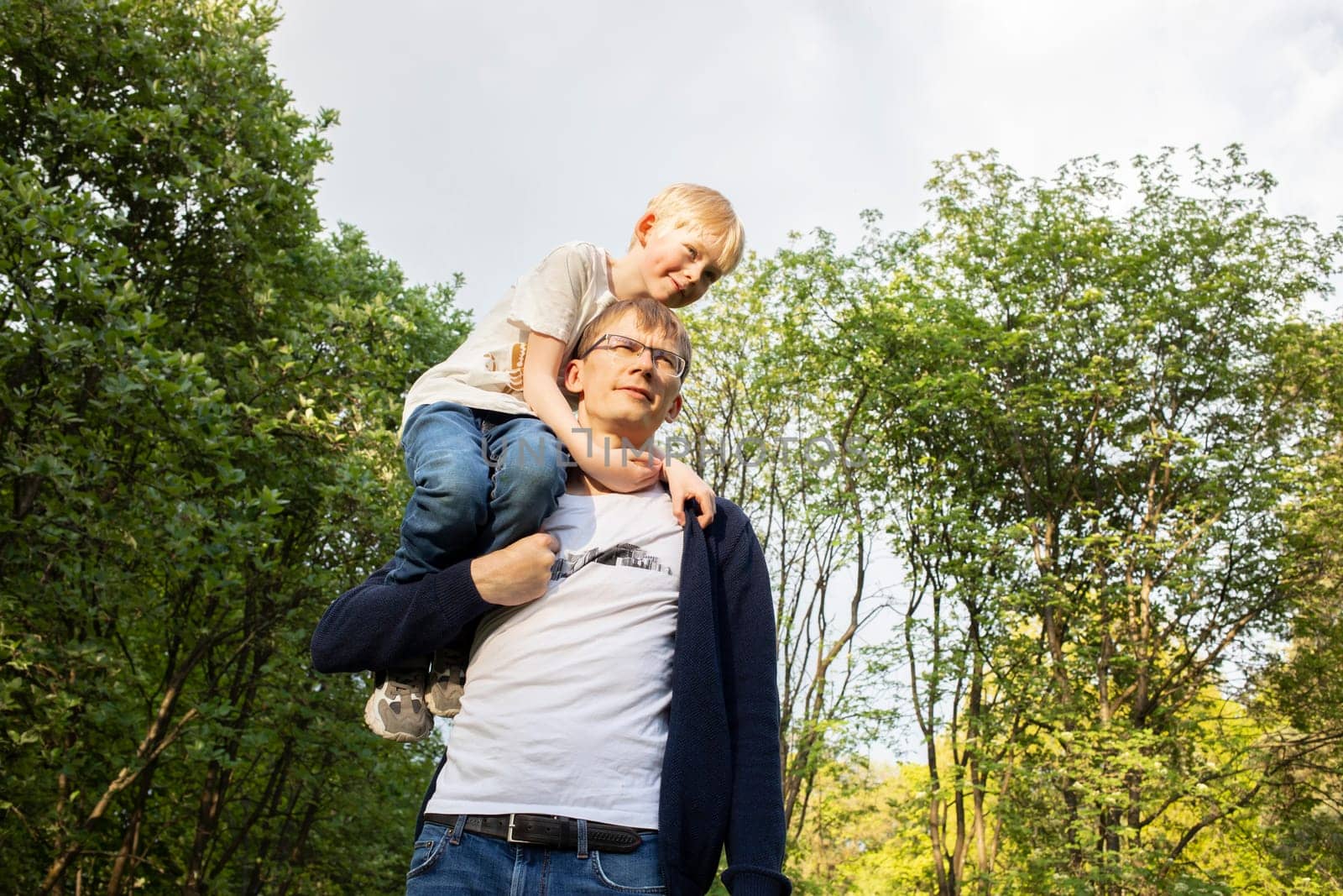 Father Carried Little Child, Son On Shoulder While Walking In Park. Summer Time. Happy Parenthood, Family Leisure Time. Emotional Connection, Love And Care. Horizontal Plane. High quality photo