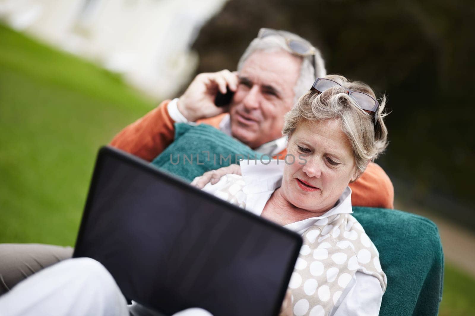 Phone call, laptop and travel with an old couple in a hotel garden for vacation at a luxury resort. Love, technology or communication with a senior man and woman tourist outdoor on grass at a lodge.