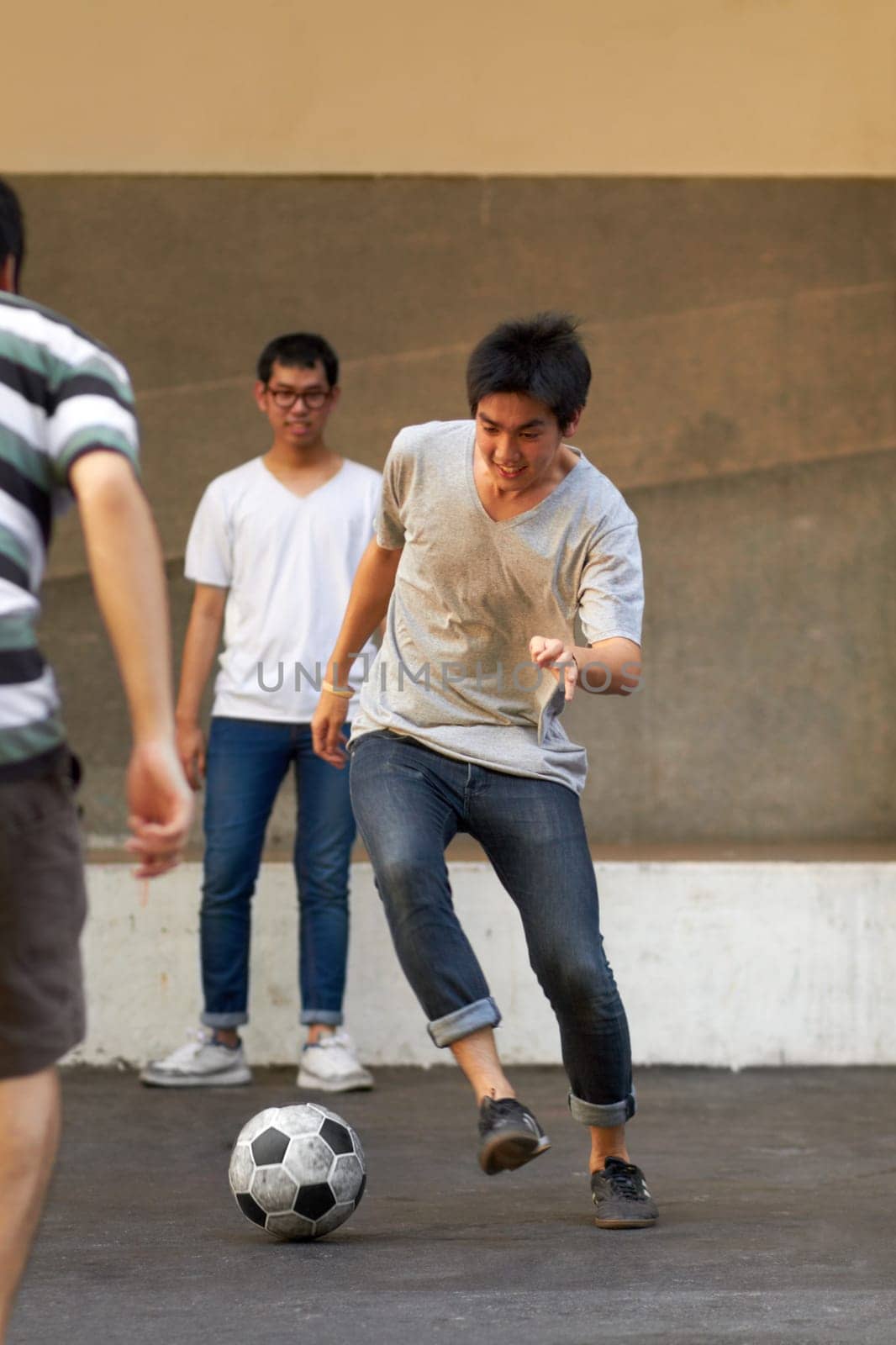 Friends in city street, man with football for sports, fun and happy energy with urban games in Korea. Game, friendship and group of young Asian men running in road with soccer ball for weekend time. by YuriArcurs