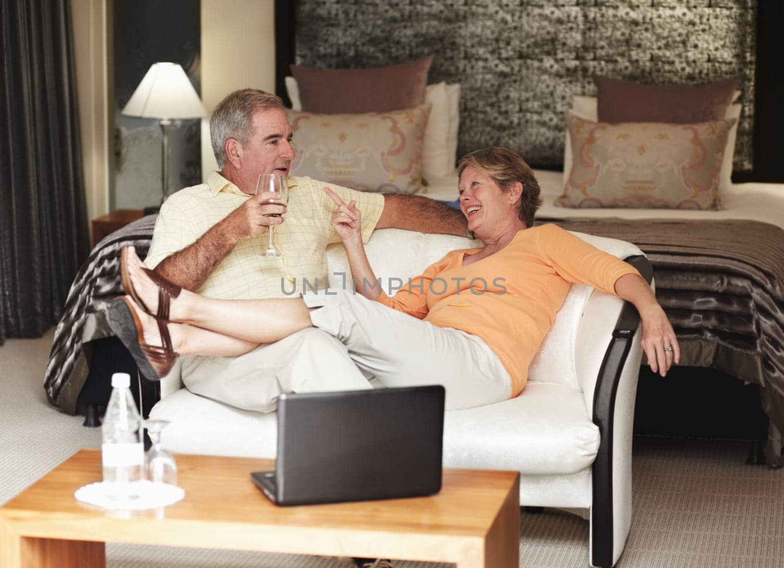 Retirement, love and an old couple drinking wine in their hotel room while on holiday or vacation together. Toast, sofa or relax with a senior man and woman bonding at a luxury resort for romance by YuriArcurs