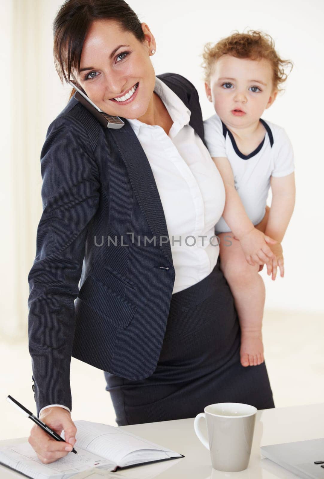 Working, writing and mother with a baby, phone and notes on a call with client, discussion or multitasking in home. Mom, time management and care for child, business and professional career success by YuriArcurs