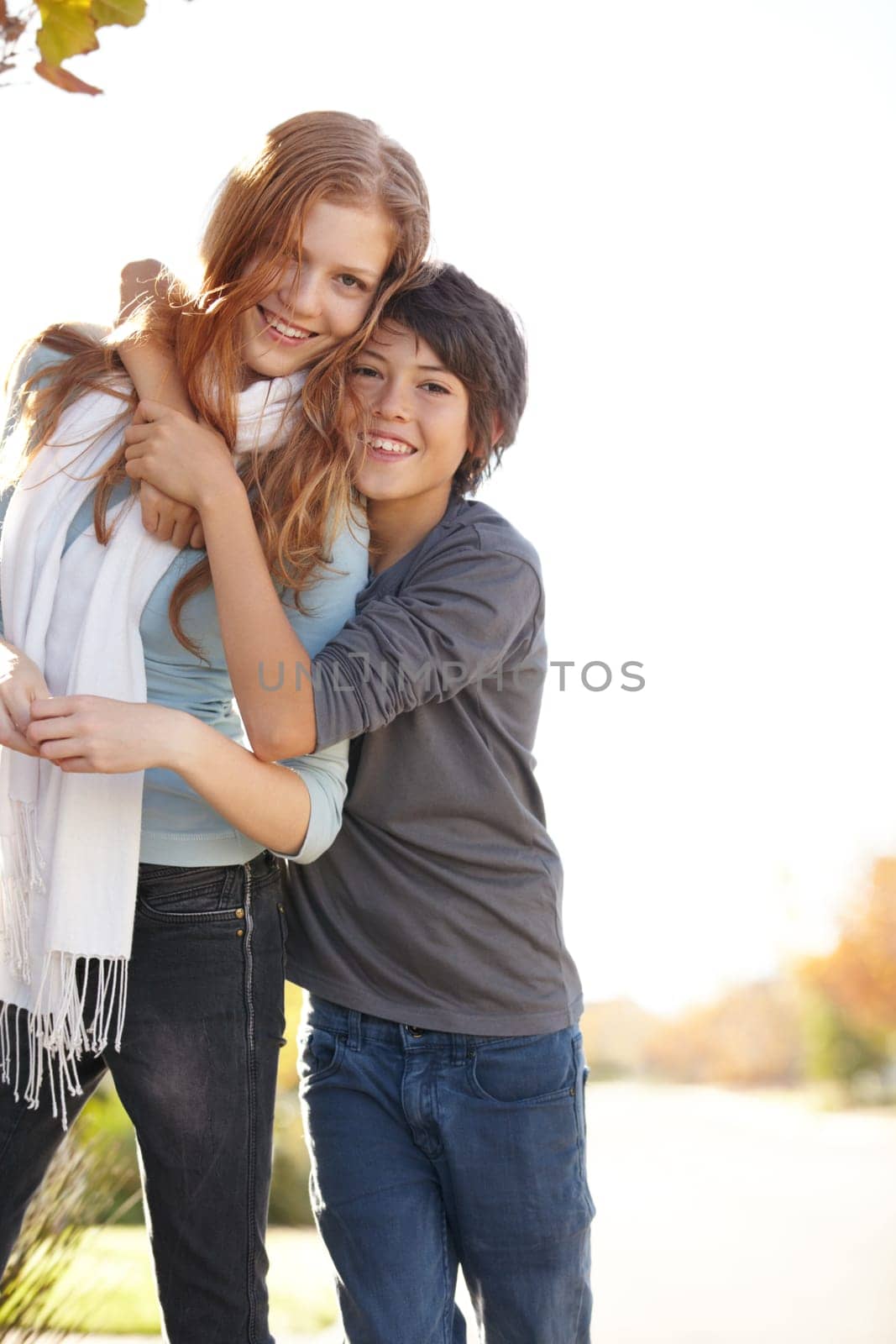 Love, portrait of brother with sister and hug outdoors for support with a lens flare with smile. Care or bonding time, family and happy people hugging outside together for health wellness in nature.