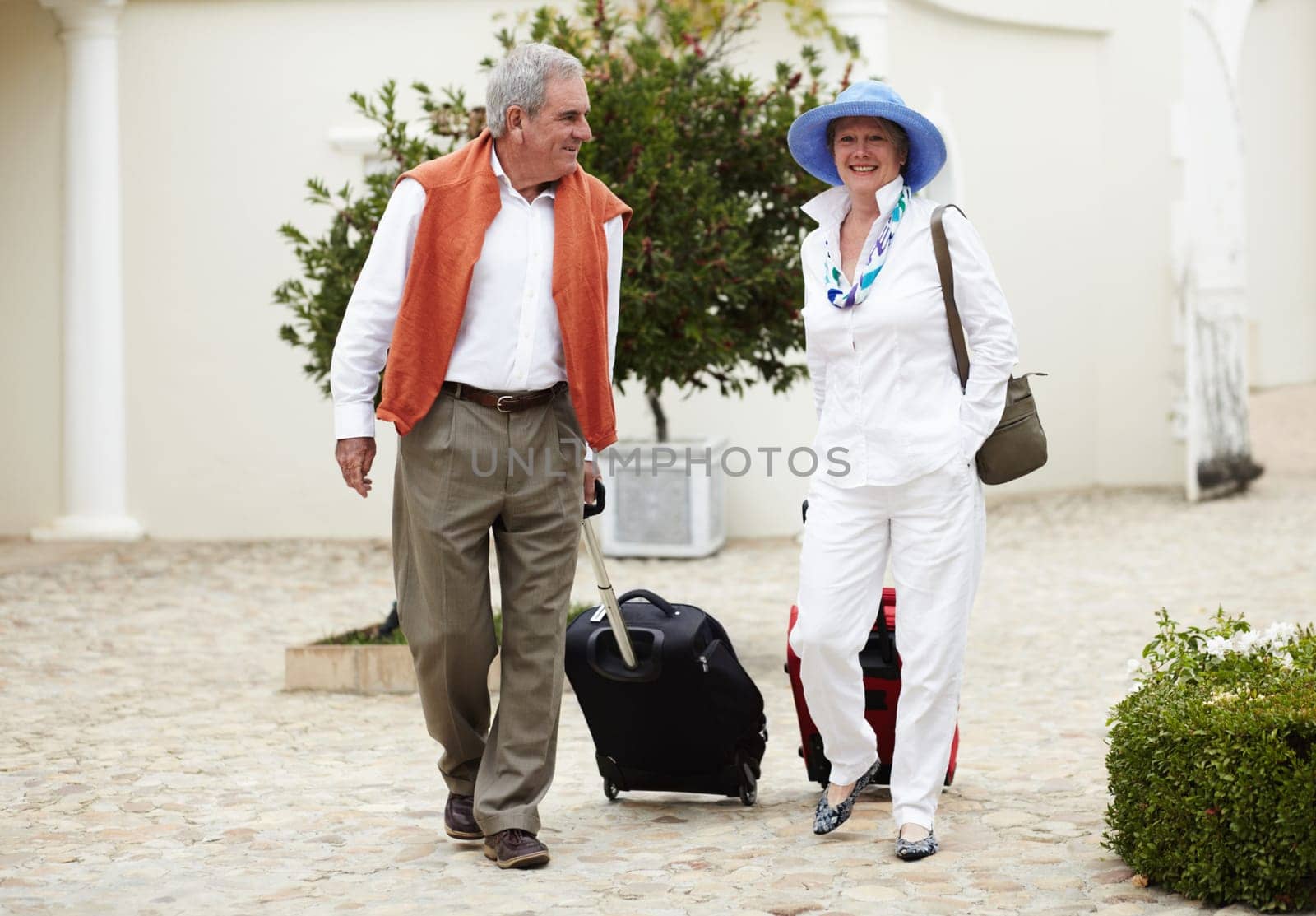 Travel, suitcase and senior couple walking on vacation in a holiday location happy in retirement together at a hotel. Bag, smile and elderly people on a journey or man and woman walk in happiness.