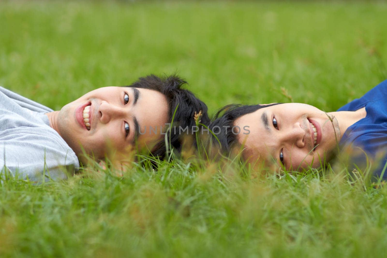 Happy, relax and portrait of a gay couple in the grass for love, bonding and happiness in a park. Smile, lgbtq and Asian men in nature for a date, romance and relaxing together on a lawn or field by YuriArcurs