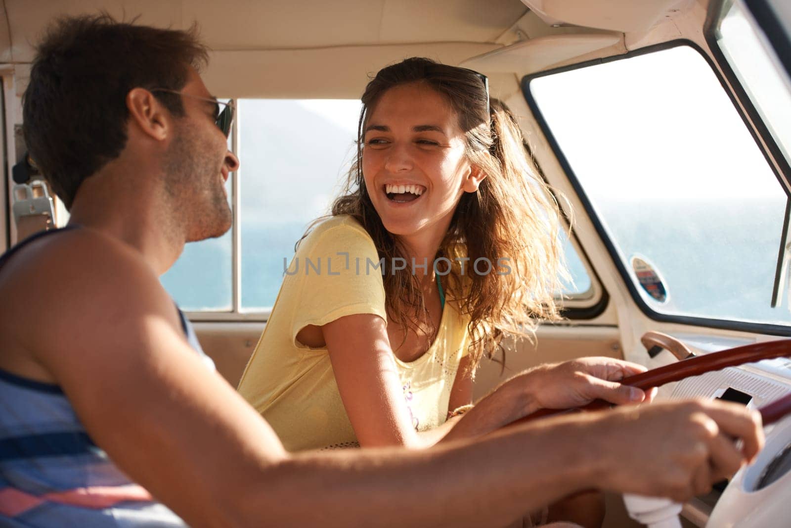 Happy couple, driving and laughing for funny road trip, travel or summer holiday weekend in the car. Man and woman traveling in mini van with laugh and smile for fun discussion or joke on journey.