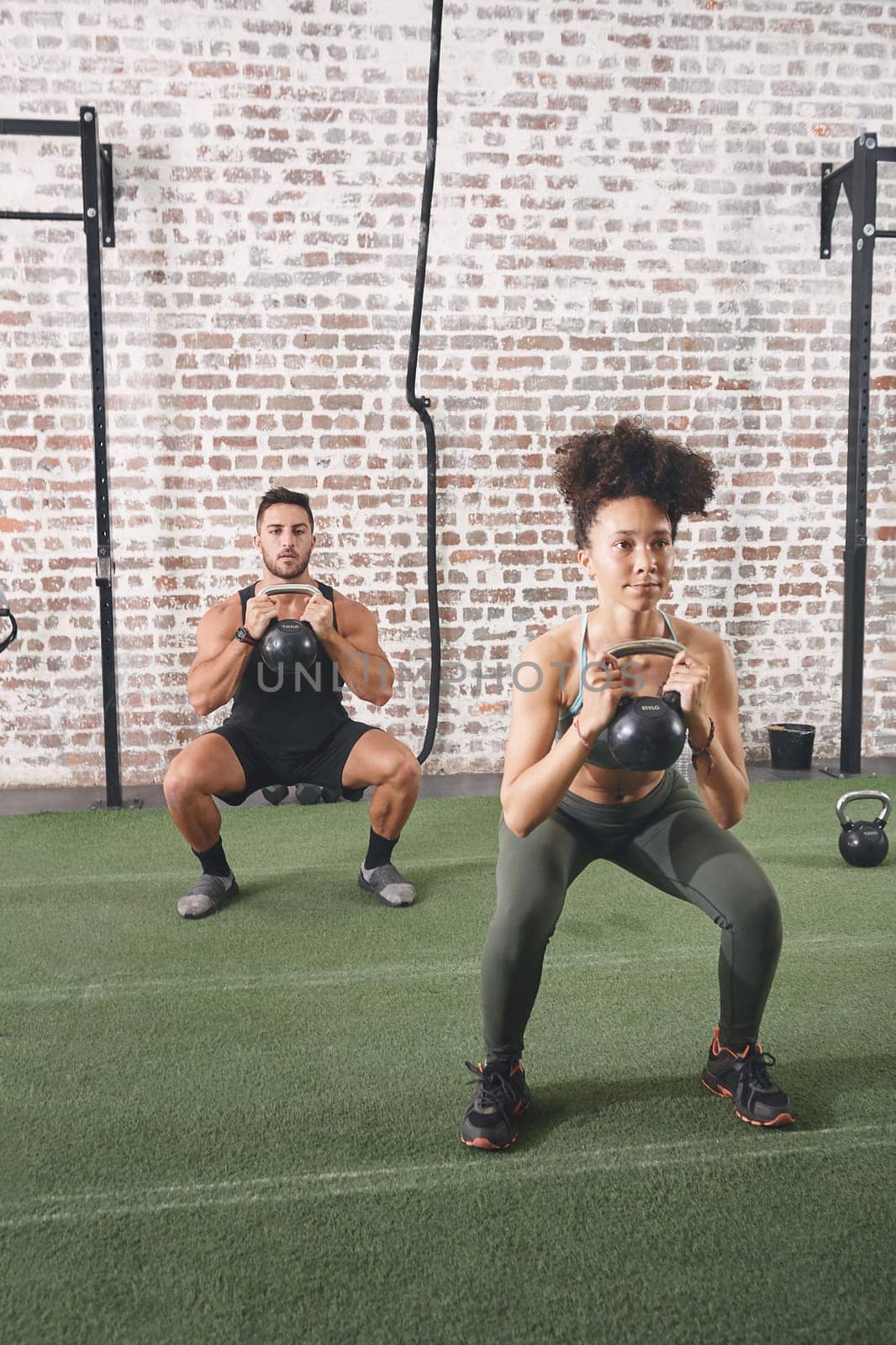 Discipline is the one thing needed to achieve any goal. two people holding kettlebells while doing squats at the gym