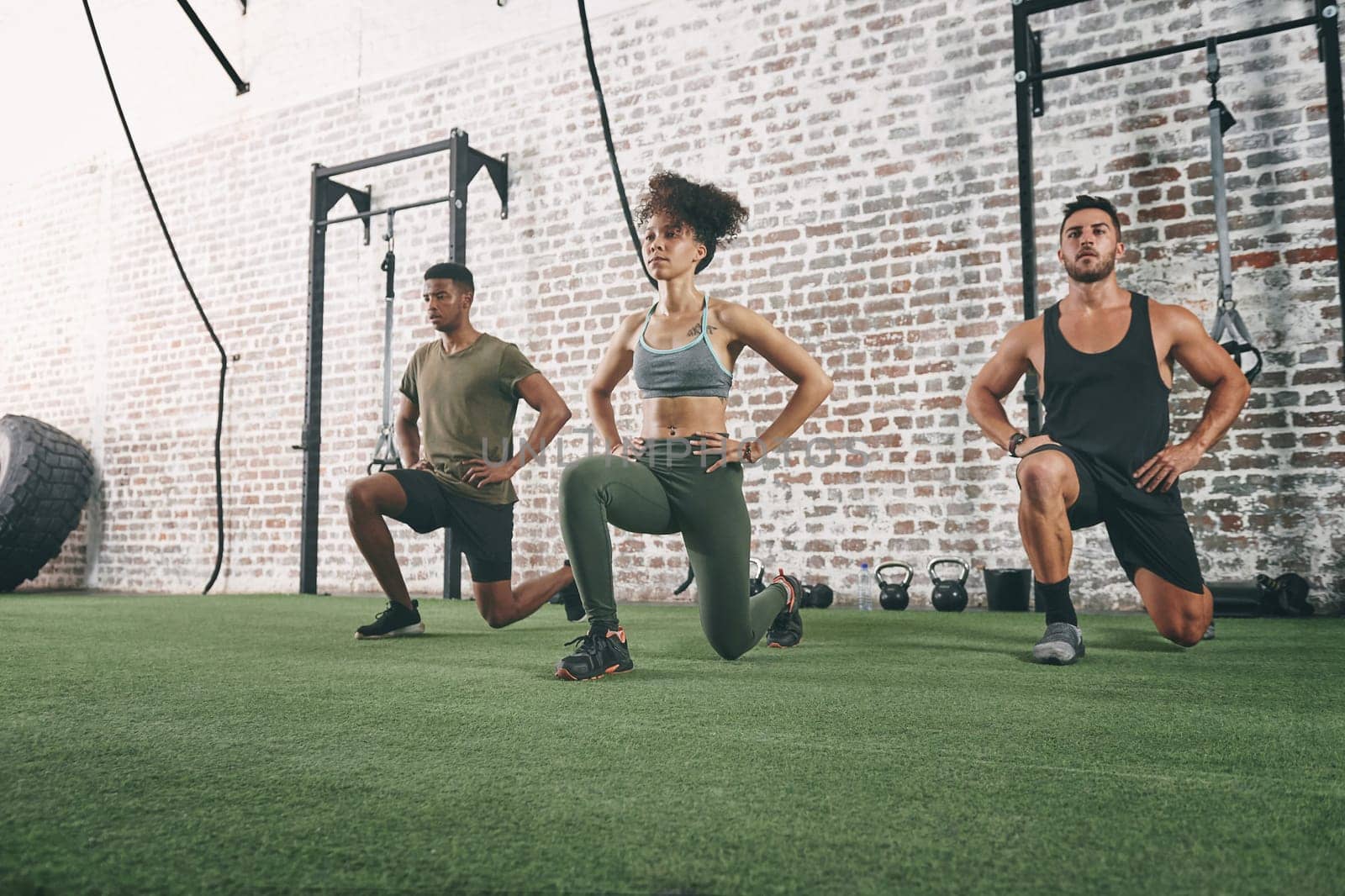 Doing it together is what keeps us motivated. a fitness group doing lunges while working out at the gym. by YuriArcurs