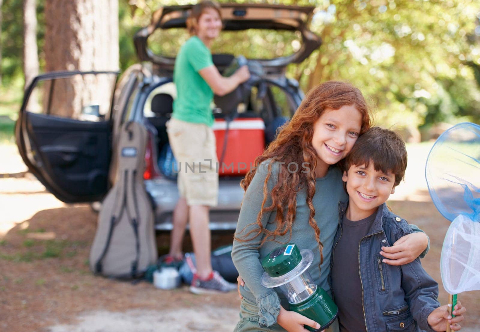 Happy siblings, portrait and hug for road trip, camping or family vacation together in nature. Sister hugging brother with smile and lantern for camp adventure, travel or holiday getaway in a forest.