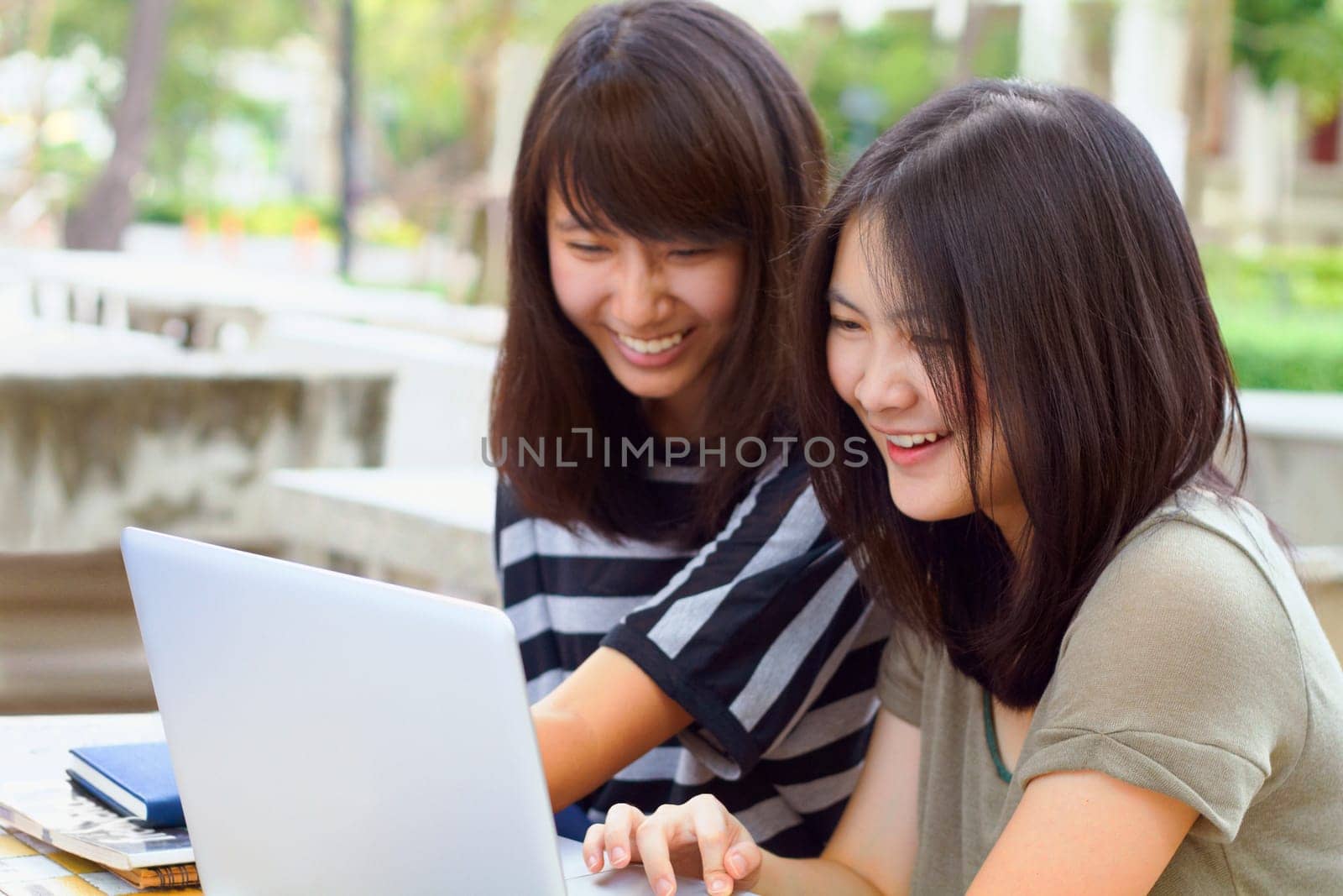 Laptop, university and female students studying outdoor on campus for a test, exam or assignment. Happy, smile and women doing research or browsing for education information on a computer at college