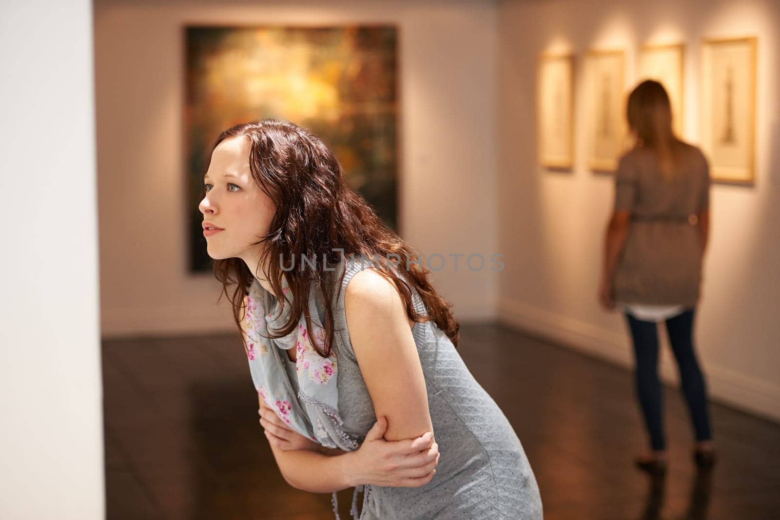 Gallery, woman and studying art at exhibition, museum or creative painting on a wall for a show in artist studio. Study, thinking and girl with focus on abstract paintings, culture or artwork buyer by YuriArcurs