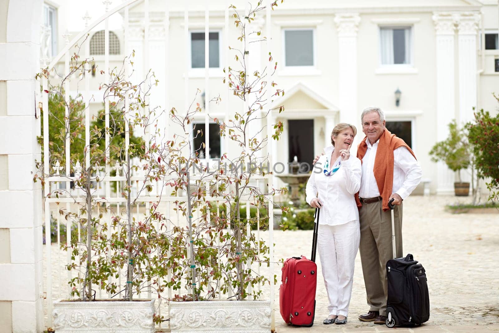Travel, hotel and senior couple relax on vacation with suitcase in a holiday location happy in retirement together. Bag, smile and elderly people on a journey or man and woman pointing in happiness.