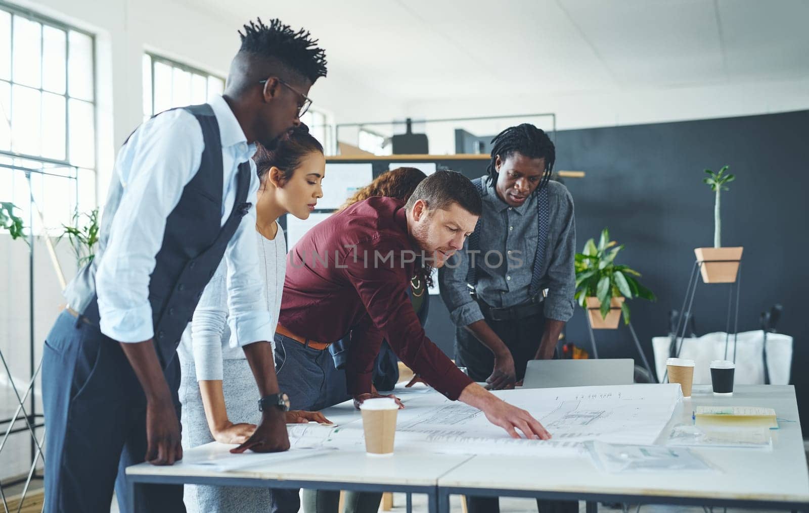 Being careful about detail. a team of professionals working on blueprints in an office. by YuriArcurs