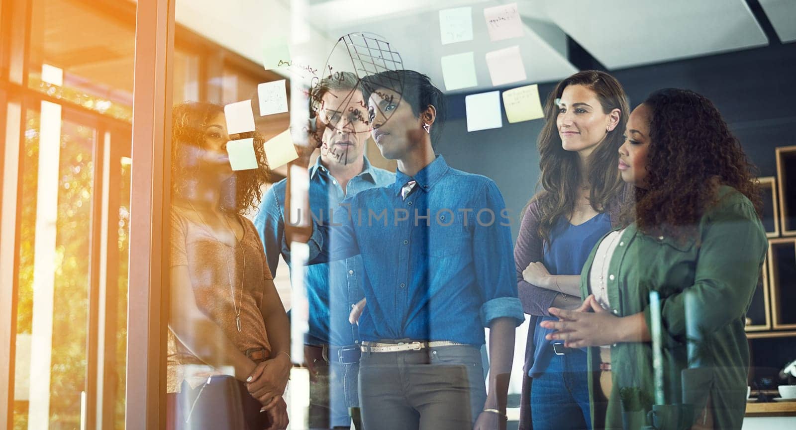 Strive for progress above simply perfection. a group of businesspeople brainstorming with notes on a glass wall in an office