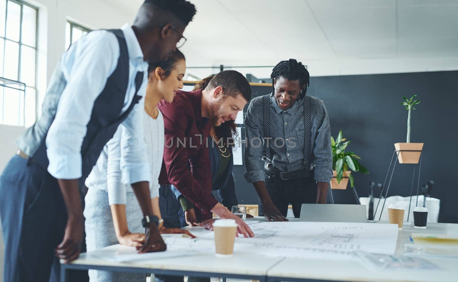 Lets turn this land into something amazing. a team of professionals working on blueprints in an office. by YuriArcurs