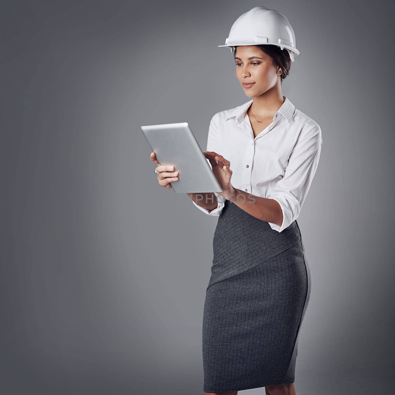 Shes going to exceed their expectatios. a well-dressed civil engineer using her tablet while standing in the studio
