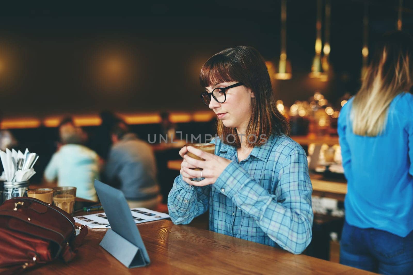 Free wifi means endless streaming. an attractive young woman using a digital tablet in a cafe. by YuriArcurs