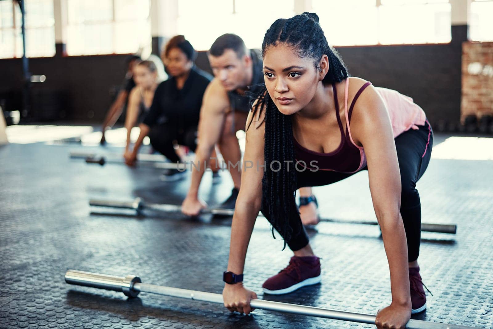 Im doing this for me and a sexier body. a fitness group using steel bars in their session at the gym. by YuriArcurs