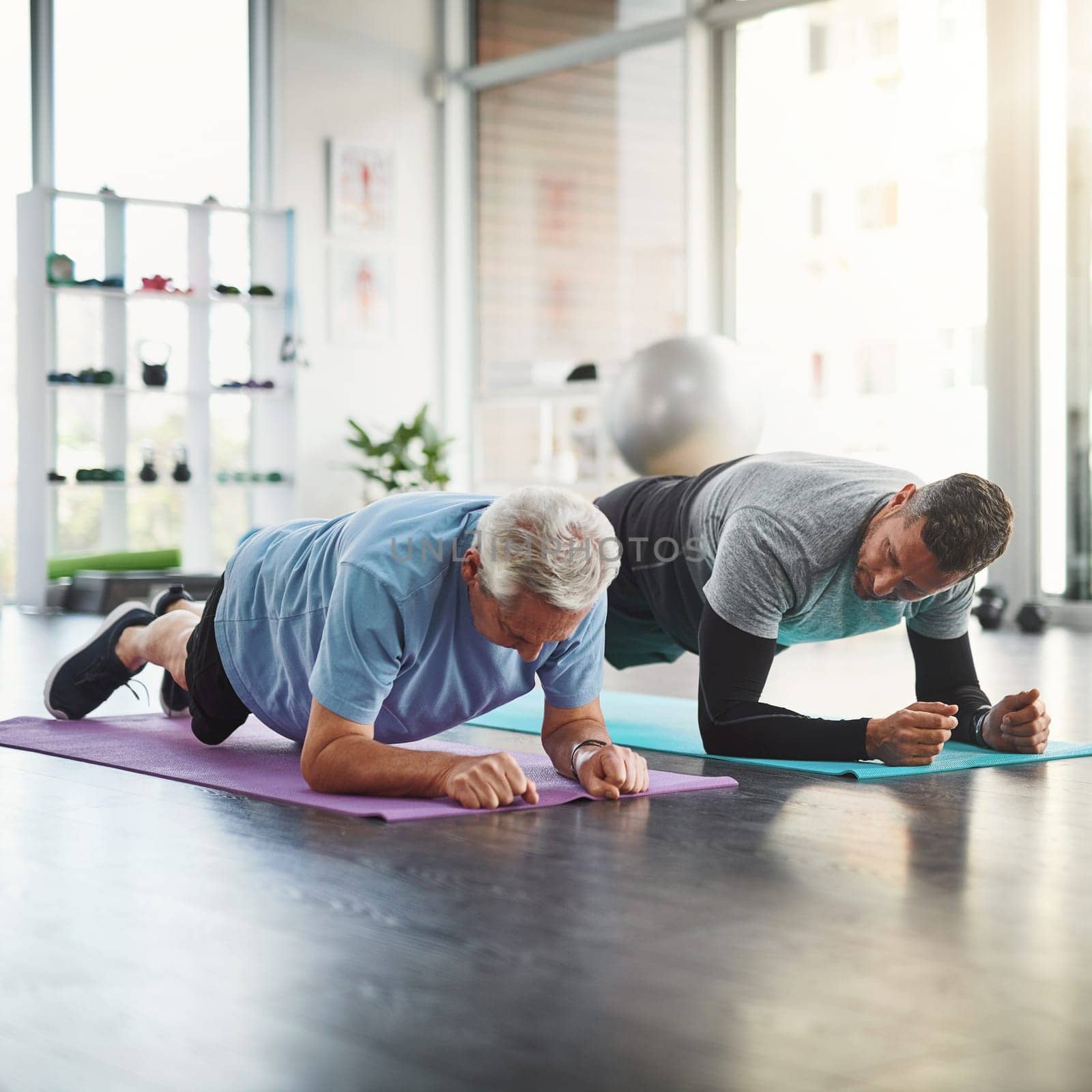 Getting fitter and more flexible. a young male physiotherapist assisting a senior patient in recovery. by YuriArcurs