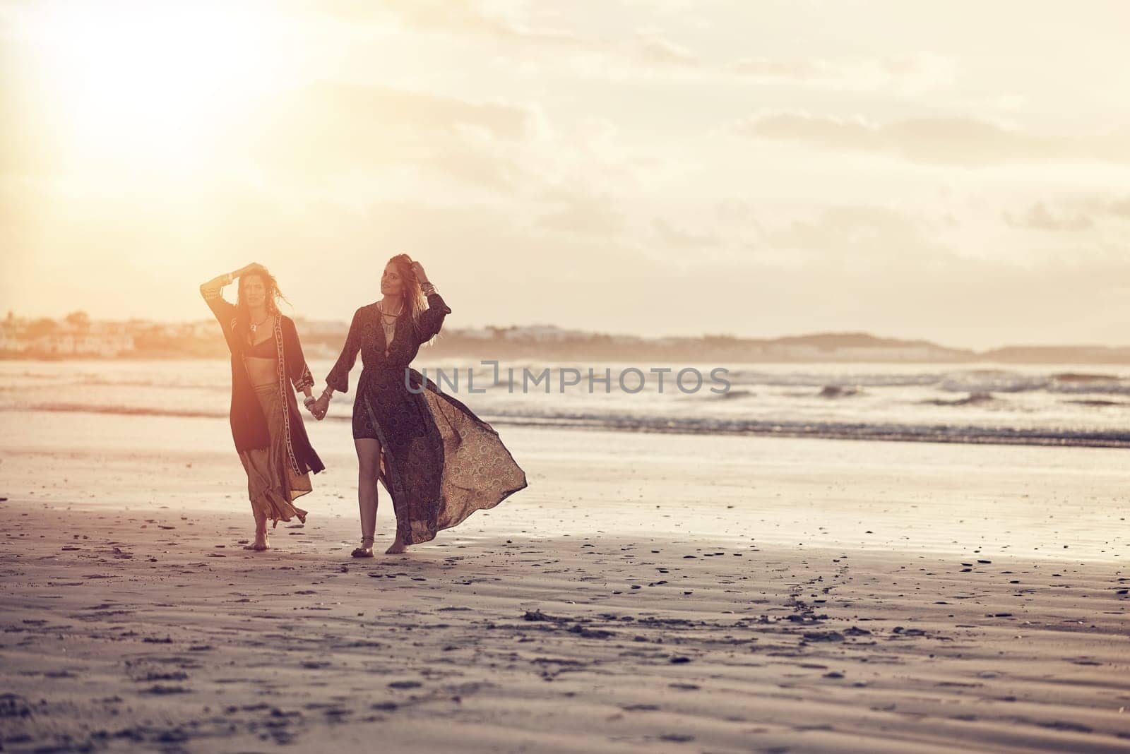 We live by the sun. two young women spending the day at the beach at sunset. by YuriArcurs