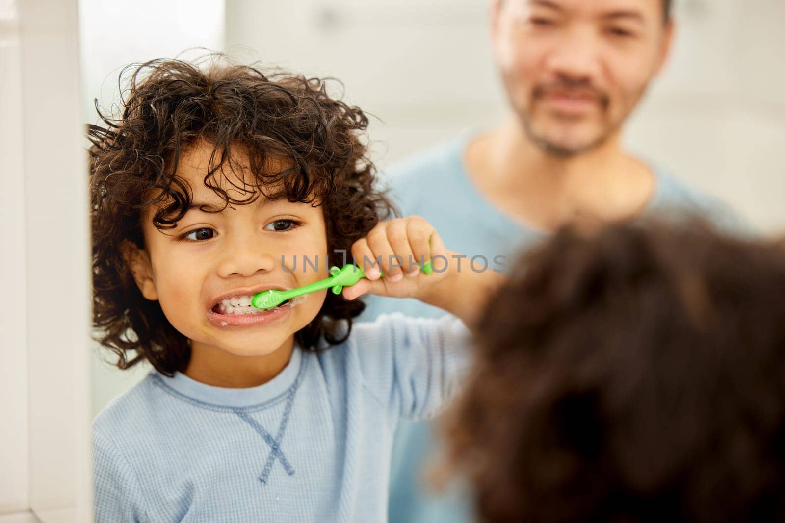 Face, mirror and child brushing teeth in a family home bathroom for health and wellness. Reflection of a latino boy kid with his father to learn about dental, oral and mouth care with a toothbrush by YuriArcurs