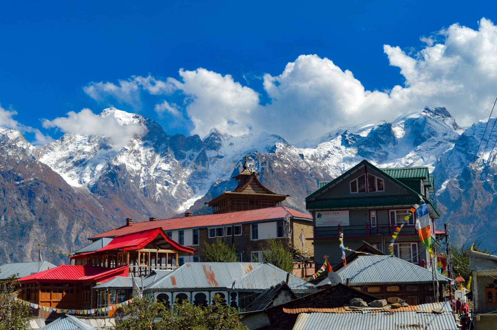 A Buddhist Monastery against show covered mountain with floating clouds in the background. Kaza Himachal Pradesh India South Asia Pacific December 26, 2021