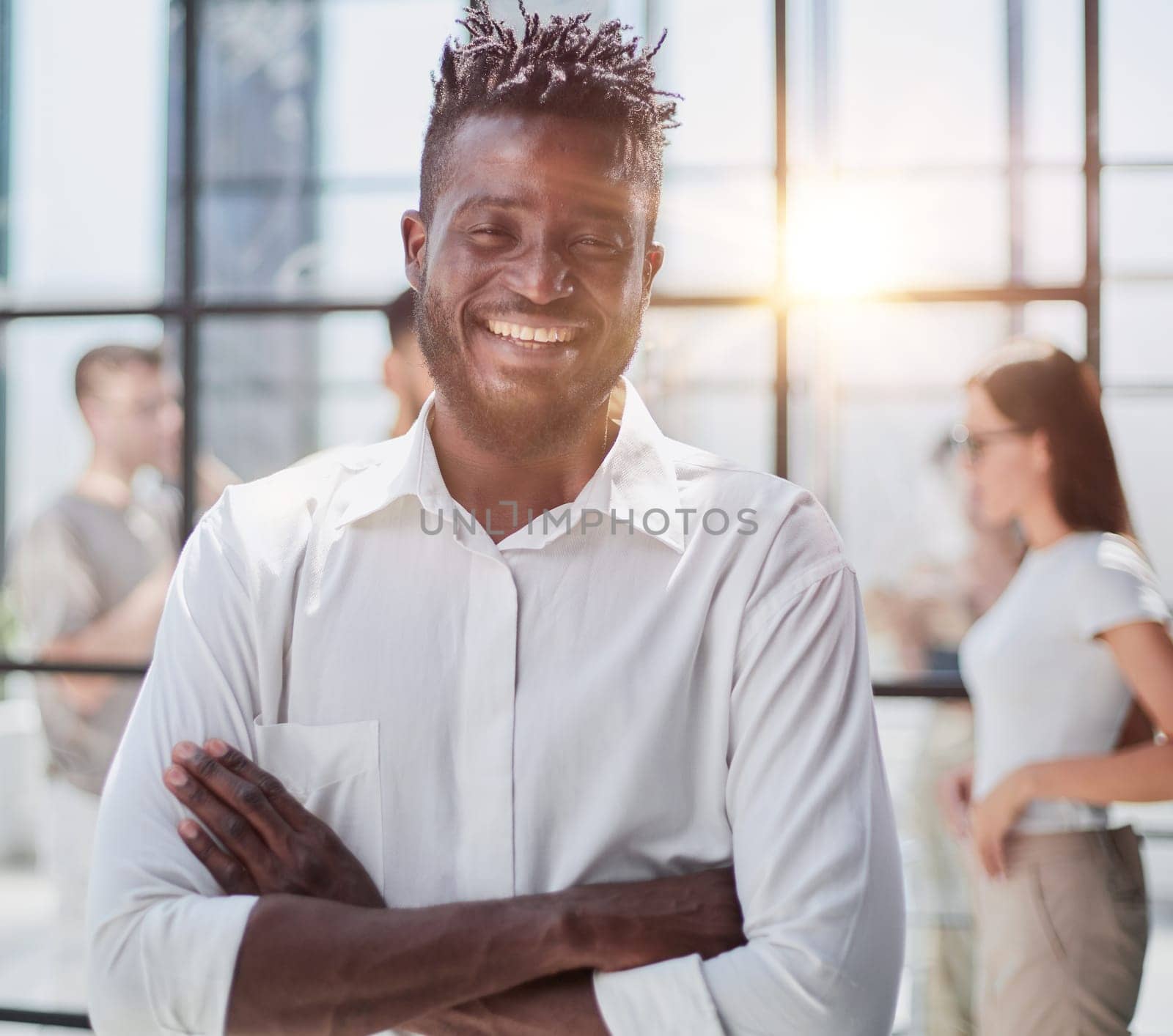 Portrait of smiling African American business man with executives working on laptop in background.