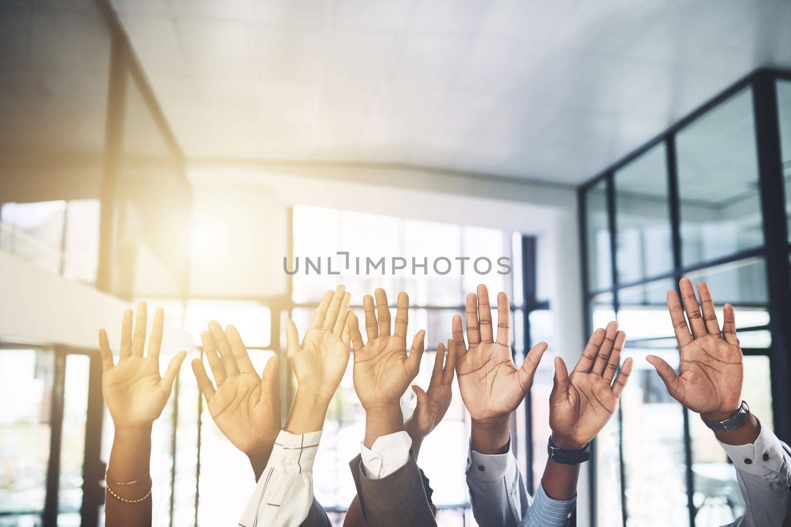 We would like to volunteer our services. Closeup shot of a group of businesspeople raising their hands in an office. by YuriArcurs