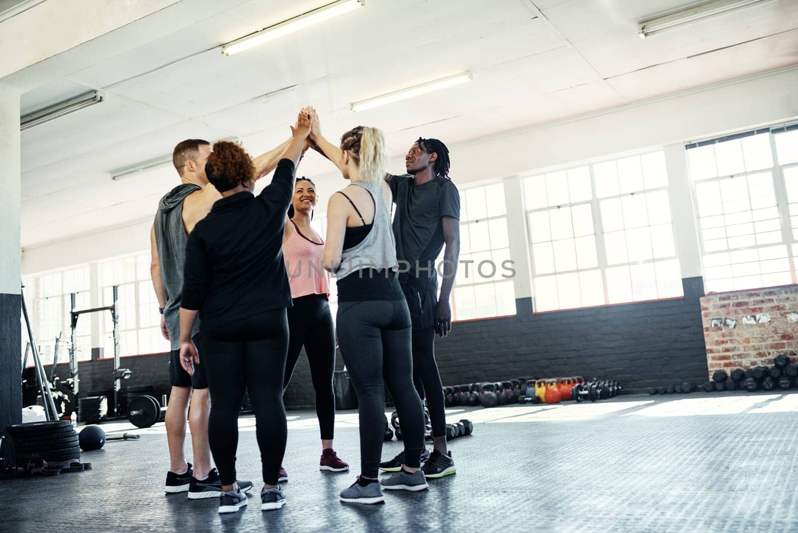 Only we can do this. a cheerful young group of people forming a huddle together before a workout session in a gym. by YuriArcurs