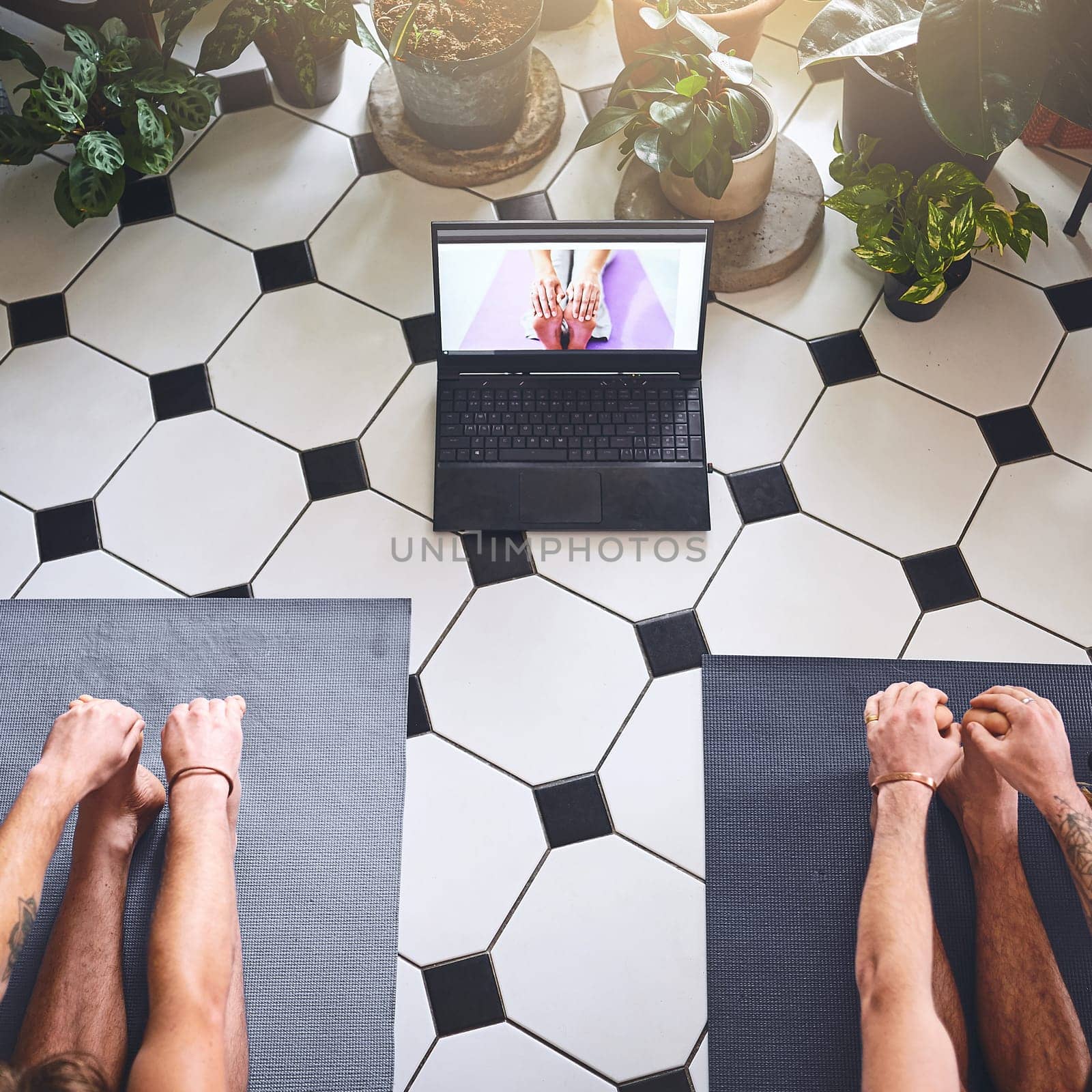 Changing times require a bit of flexibility. two men using a laptop while going through a yoga routine at home. by YuriArcurs