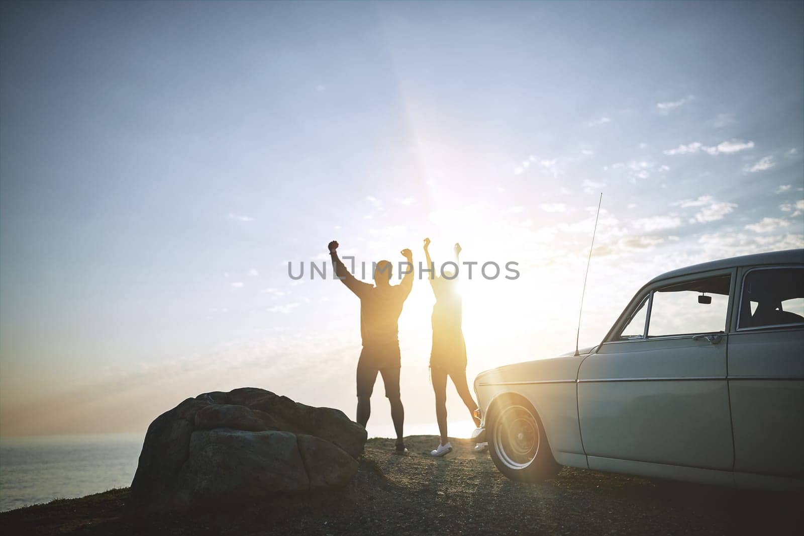 Life is pretty amazing. a young couple making a stop at the beach while out on a road trip. by YuriArcurs