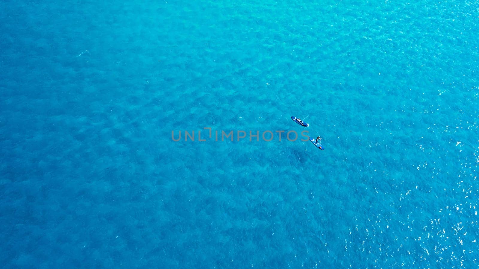 Explore the waters on a paddle boat. a man and woman paddle boarding across the sea. by YuriArcurs