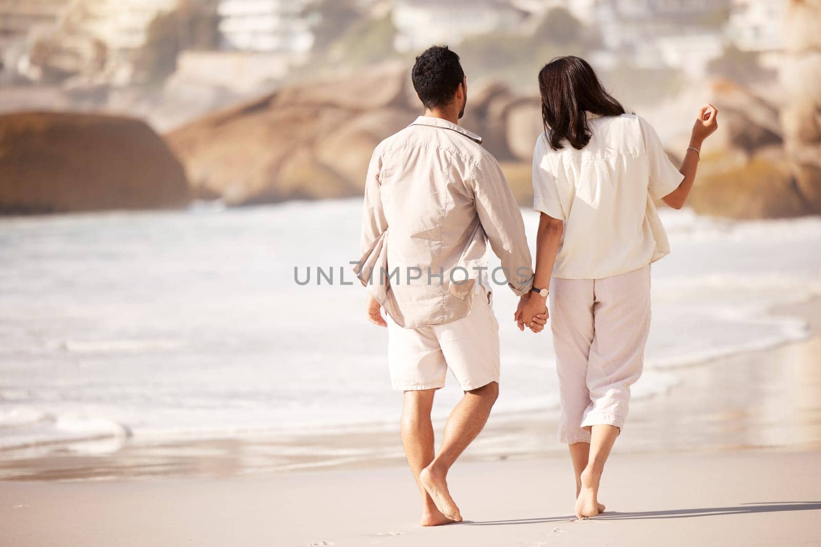 Couple walking on beach, holding hands and back view with ocean, travel and vacation with love and bonding outdoor. Mockup space, summer and people together in nature with relationship and commitment by YuriArcurs