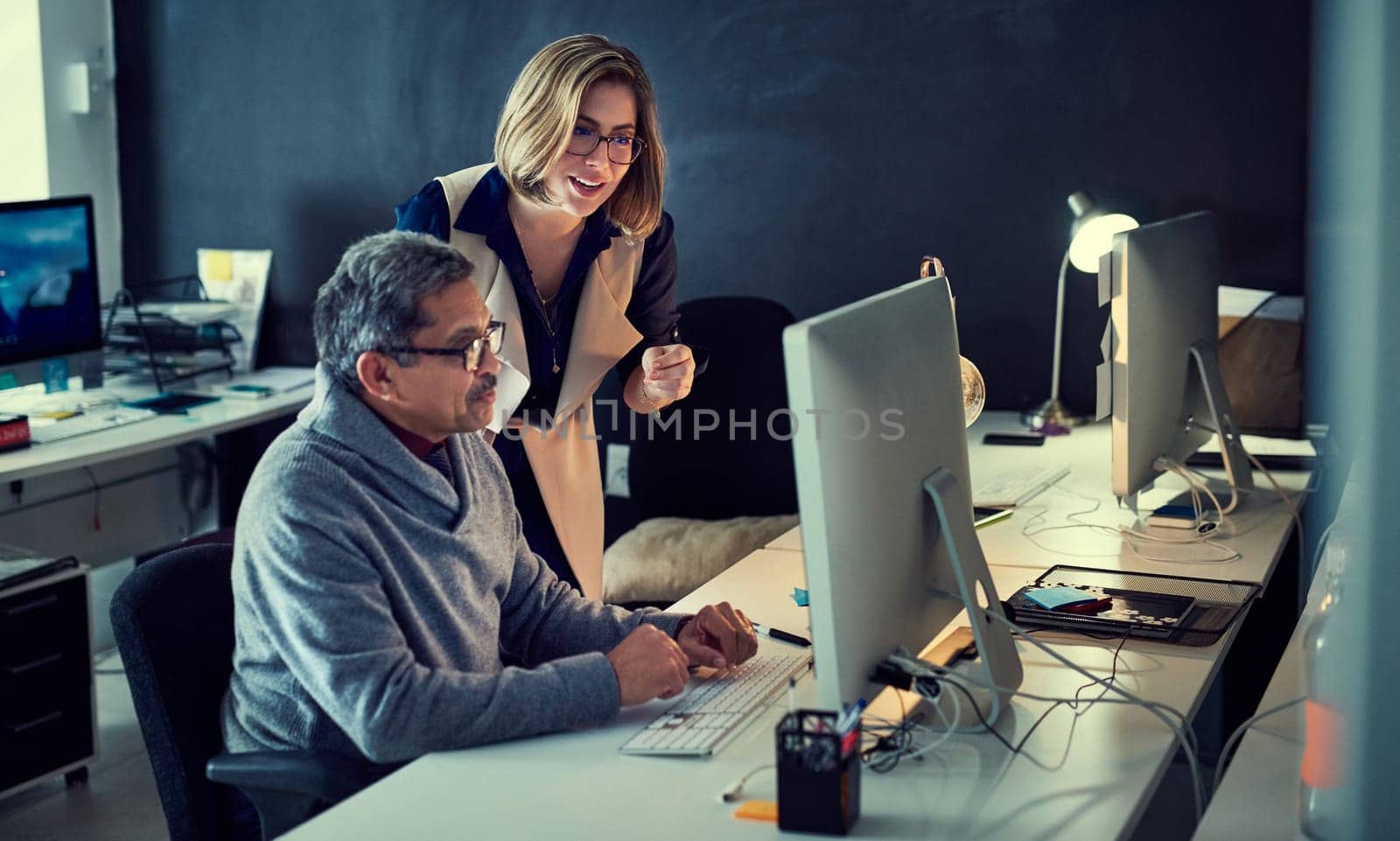 The sun may have gone down but their determination hasnt. two businesspeople working late in an office